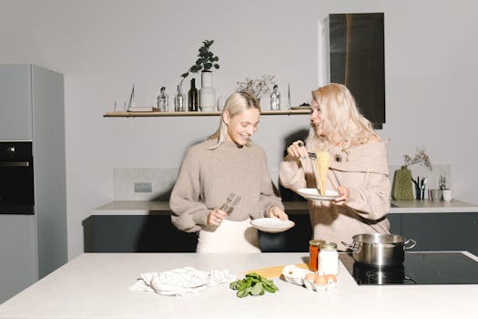 A joyful mother and daughter cooking spaghetti together in a modern kitchen.
