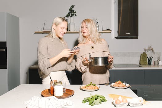 Happy mother and daughter enjoying cooking pasta in a stylish kitchen.