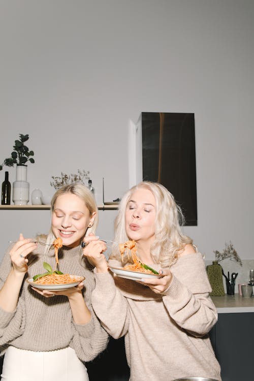 Candid Photo Of Mother And Daughter Eating Spaghetti