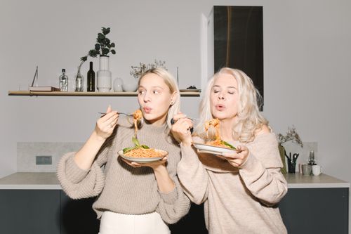 Free A candid moment of a mother and daughter enjoying homemade pasta together in a cozy kitchen. Stock Photo