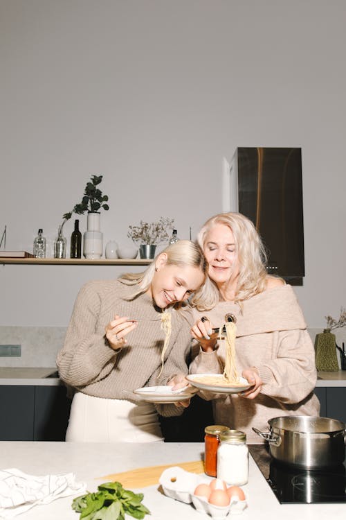 Mother And Daughter Holding Plates With Spaghetti Noodles