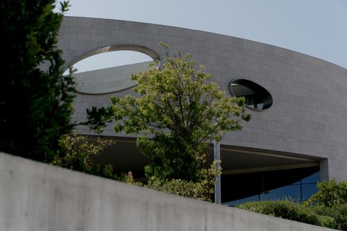 Free Modern architecture featuring a unique facade with circular windows and surrounding greenery. Stock Photo