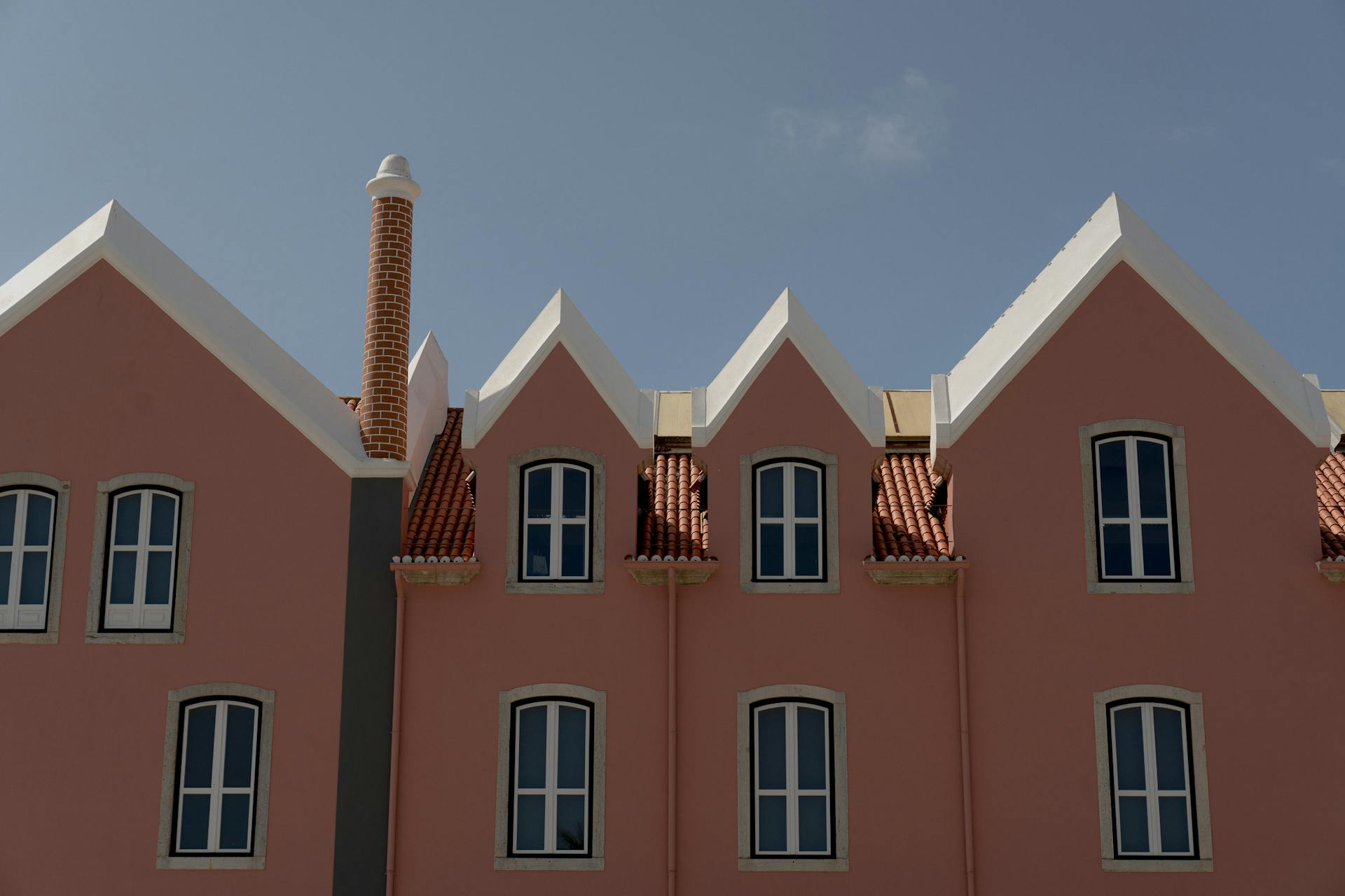 Pink building showcasing distinctive gabled roofs and elegant windows under a clear blue sky.