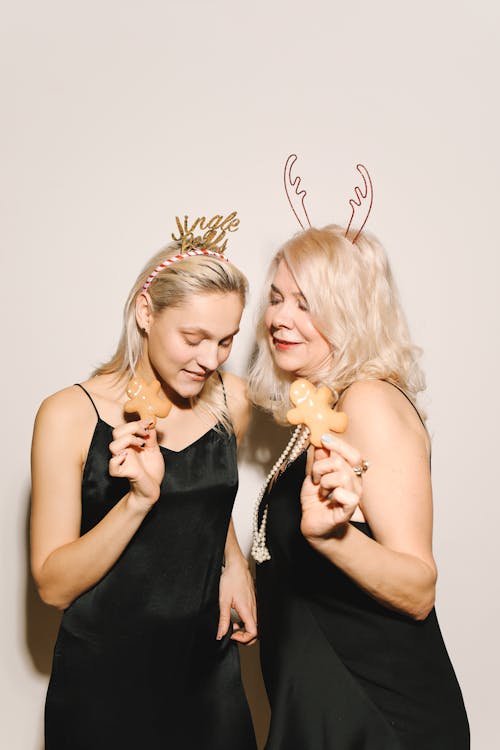 Mother And Daughter In Black Dresses Holding Gingerbread Cookies