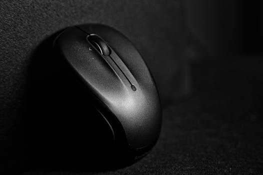 Sleek black wireless computer mouse resting on a dark surface in close-up view.