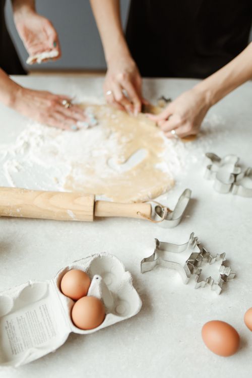 Free Hands kneading dough on a floured table with cookie cutters and eggs, perfect for baking themes. Stock Photo