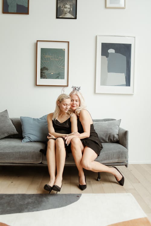 Mother And Daughter in Black Dress Sitting on Gray Couch