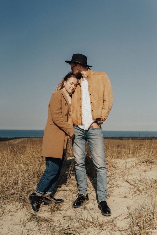 Free A couple shares a tender moment on a sandy beach under a clear sky. Stock Photo
