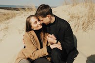 Man in Black Coat Hugging Woman in Brown Coat