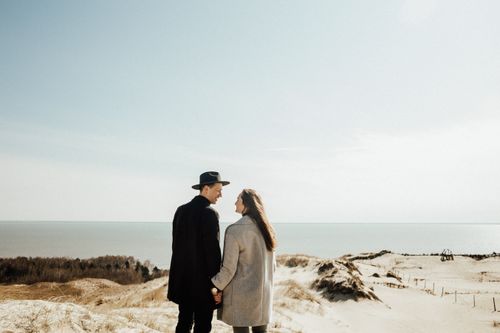Free A couple shares a romantic moment holding hands on a scenic beach. Perfect for capturing love and connection. Stock Photo