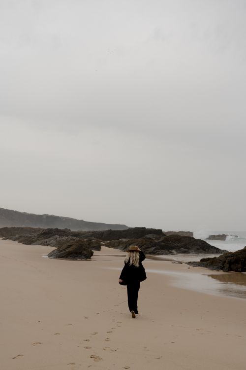 Free Woman walking on a misty beach, leaving footprints in the sand. Stock Photo