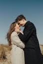 Man in Black Suit Kissing Woman in Gray Coat