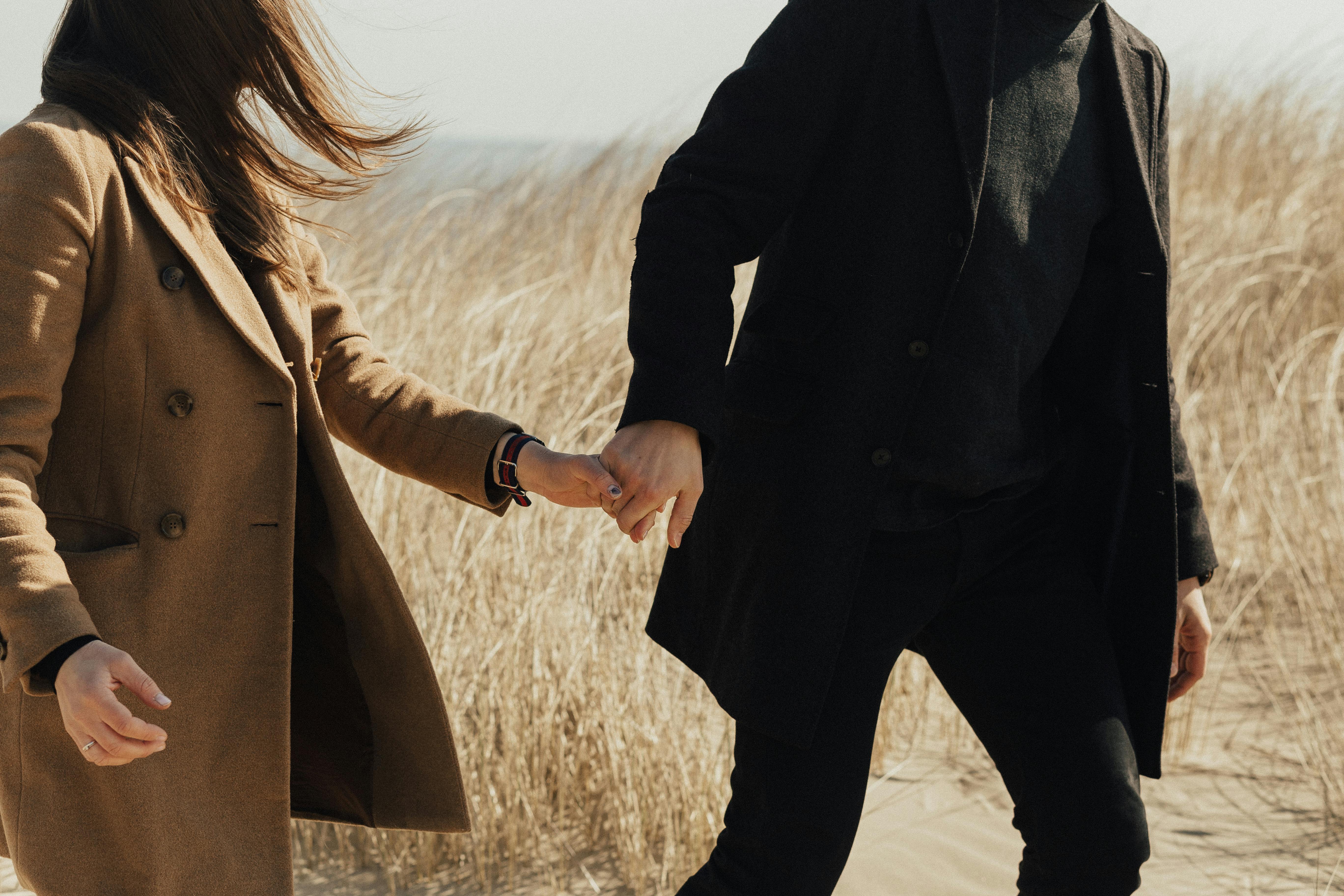 Woman in Black Coat Standing on Brown Grass Field