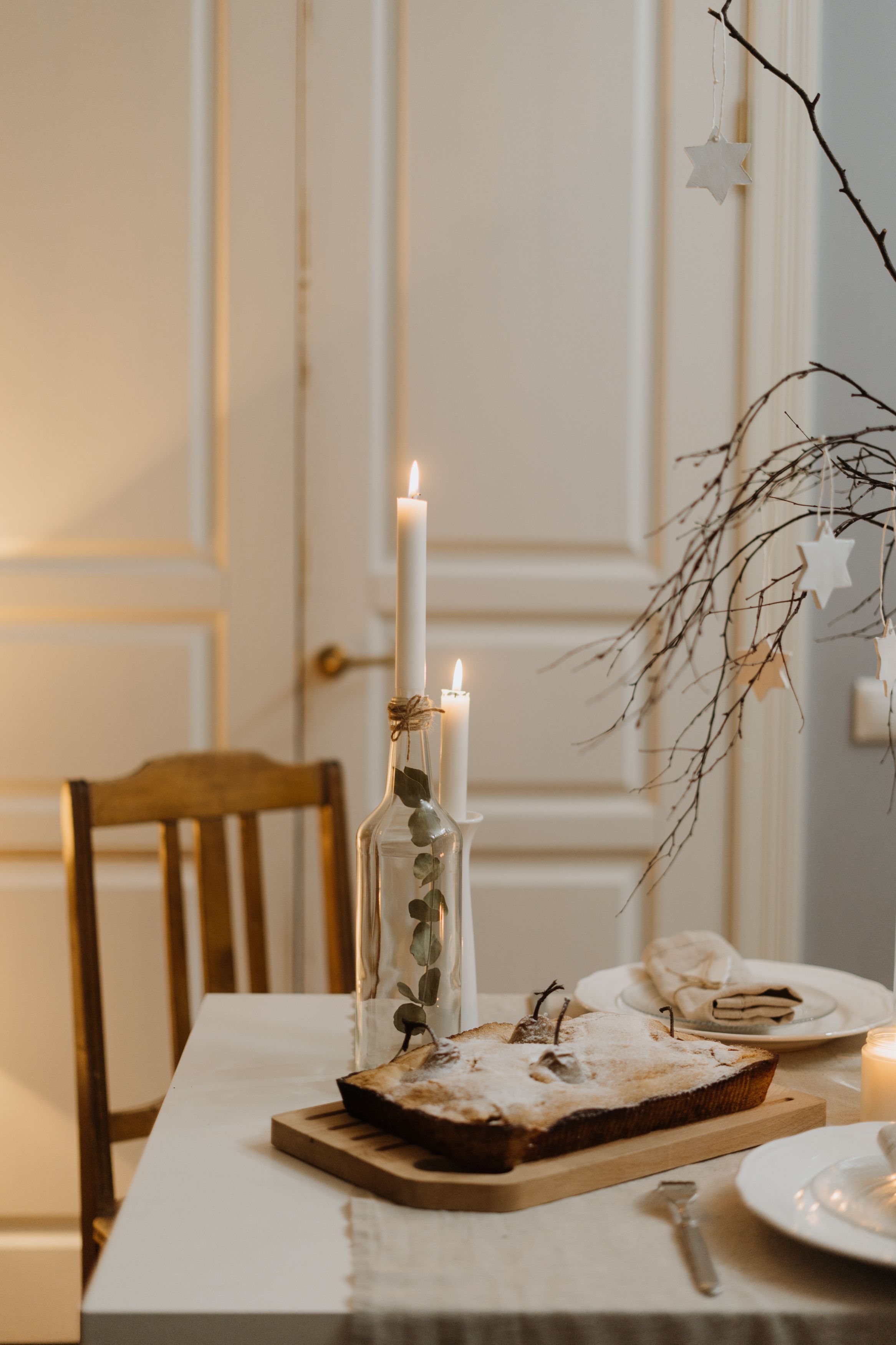 Minimalist Scandinavian Christmas table with white candles, bare branches and simple decor