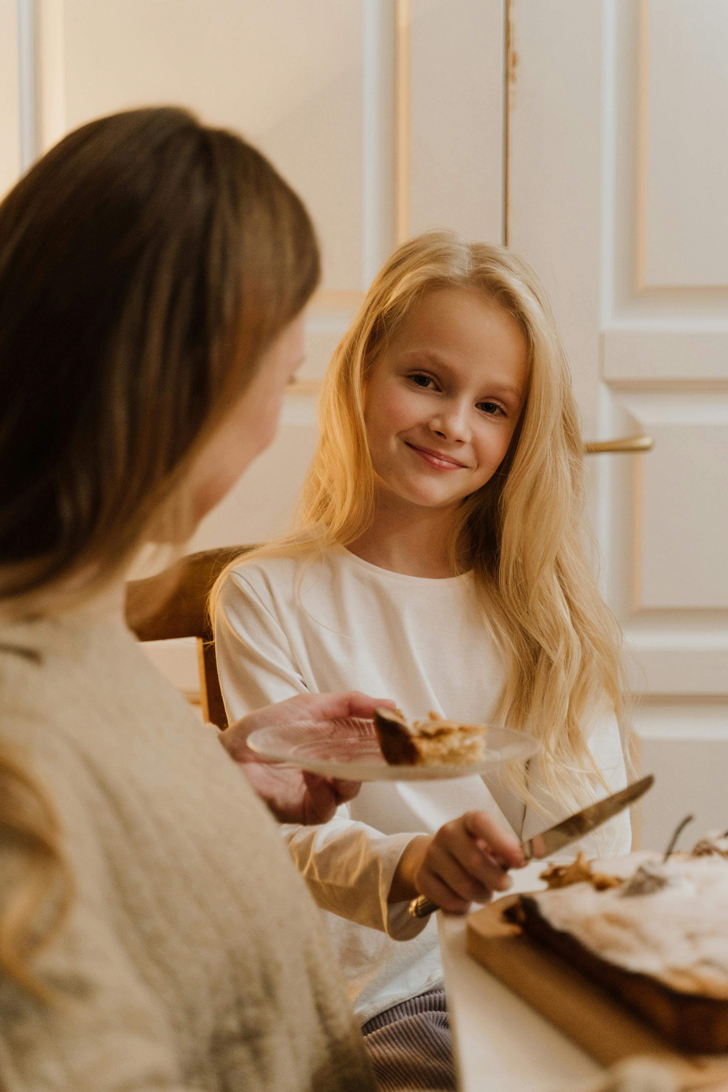 smiling girl with blonde hair holding a knife to slice a cake