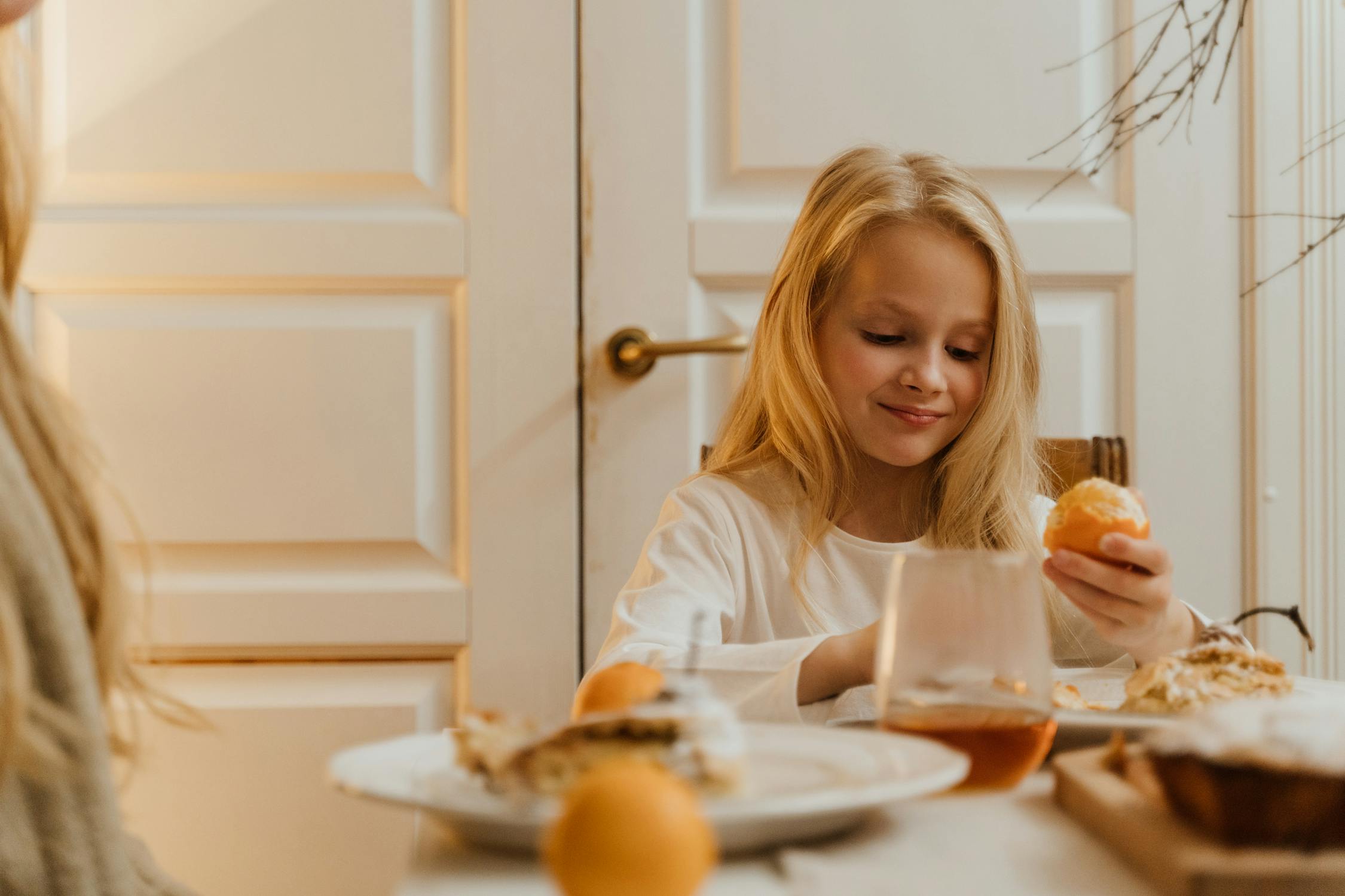 girl peeling an orange at breakfast table