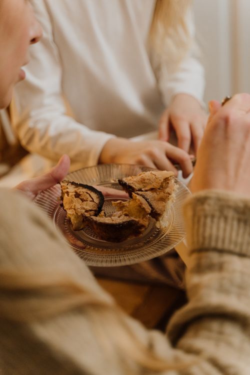 Free Two adults sharing a mouthwatering slice of cake on a cozy day indoors. Stock Photo