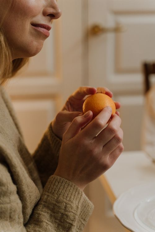 Free Close-up of a woman holding an orange indoors, capturing a warm, intimate moment. Stock Photo