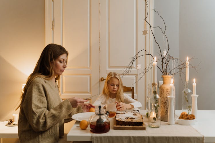 Mother And Daughter Sitting At Table At Christmas