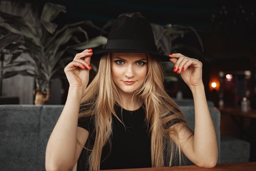 Stylish woman in hat sitting in cafe