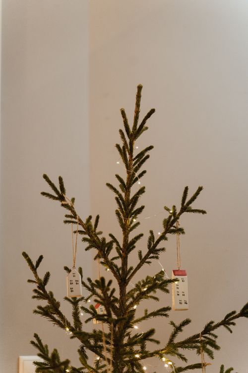 Free A simple Christmas tree adorned with tiny house ornaments and string lights, set indoors. Stock Photo