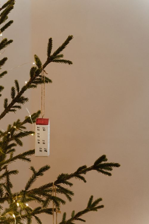 Free A minimalist holiday decor with a small house ornament on a Christmas tree branch. Stock Photo