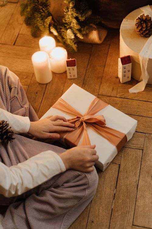 Free Warm indoor scene with a person preparing Christmas gifts and candles. Stock Photo