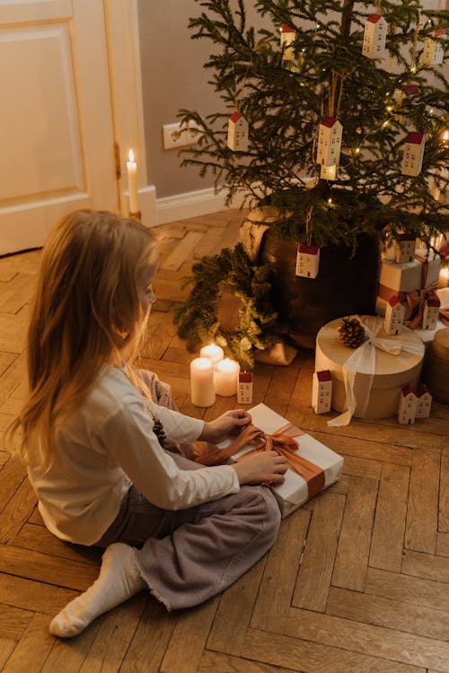 Free Girl in White Long Sleeve Shirt Sitting on Floor Opening A Gift Stock Photo
