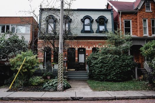 Charming Toronto townhouse with distinctive brick architecture surrounded by lush greenery.