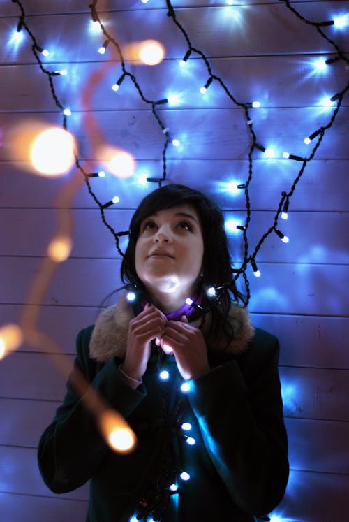 Woman in Black Coat Looking At String Lights