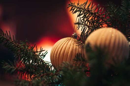 Close-up of elegant Christmas baubles on evergreen branches with a warm glowing background.