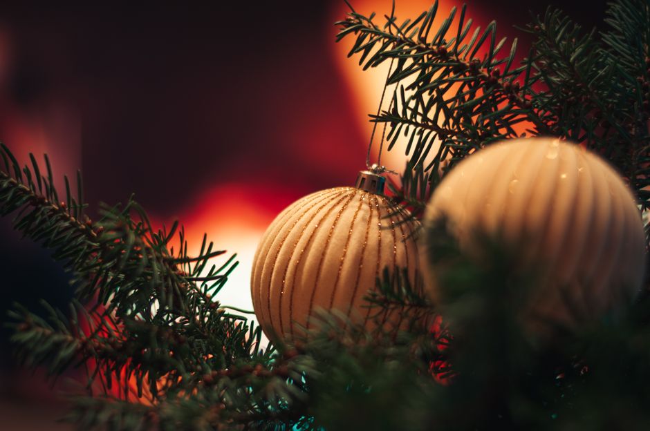 Close-up of elegant Christmas baubles on evergreen branches with a warm glowing background.