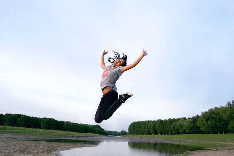 A Woman Jumping Near A Lake