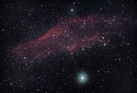 A dense field of faint stars and a soft galaxy glow against a black sky