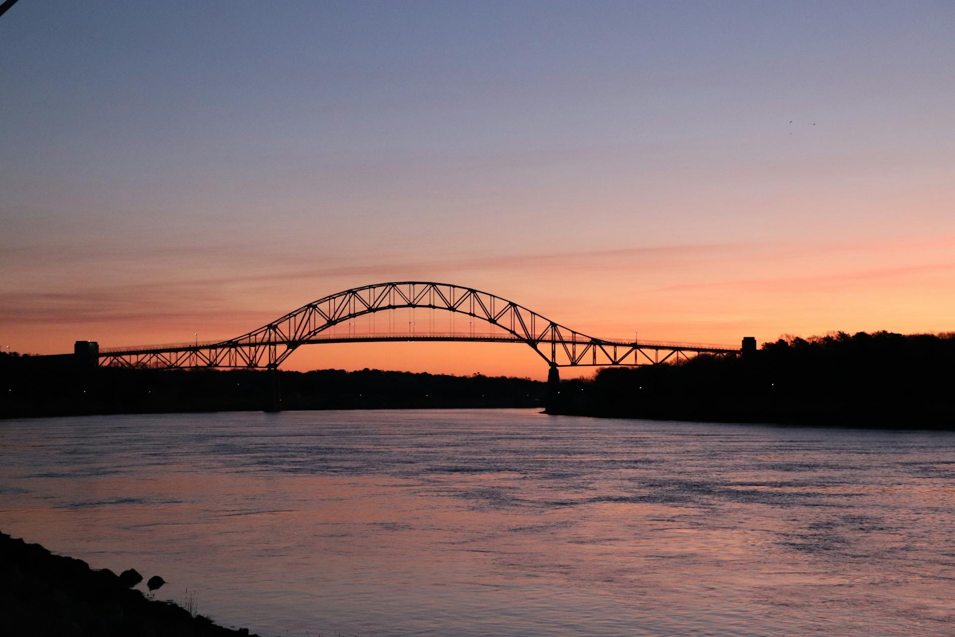 Stunning sunset view of Bourne Bridge silhouetted against the sky over Cape Cod Canal.