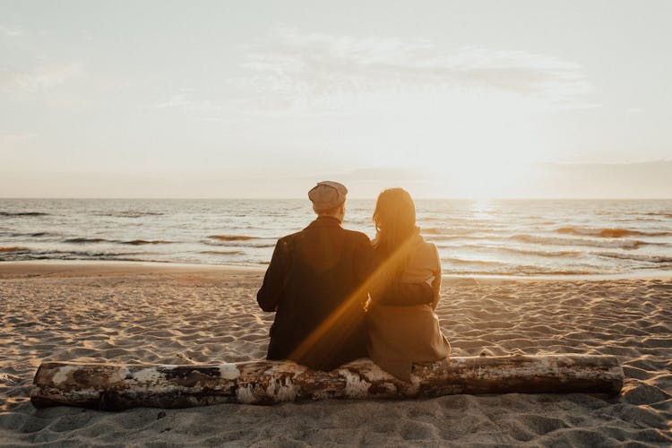 A Couple Sitting On A Beach