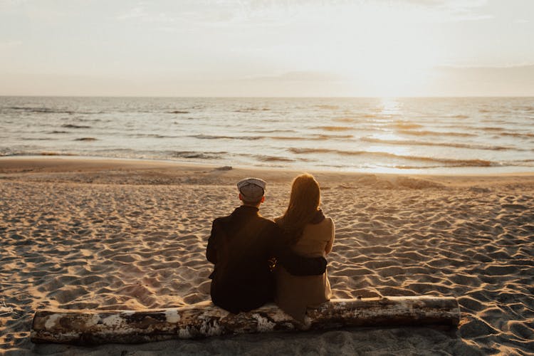 A Couple Sitting On A Beach