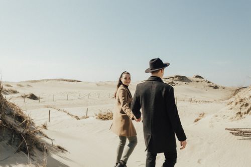 Free A couple holding hands and walking in a serene desert landscape under a clear blue sky. Stock Photo
