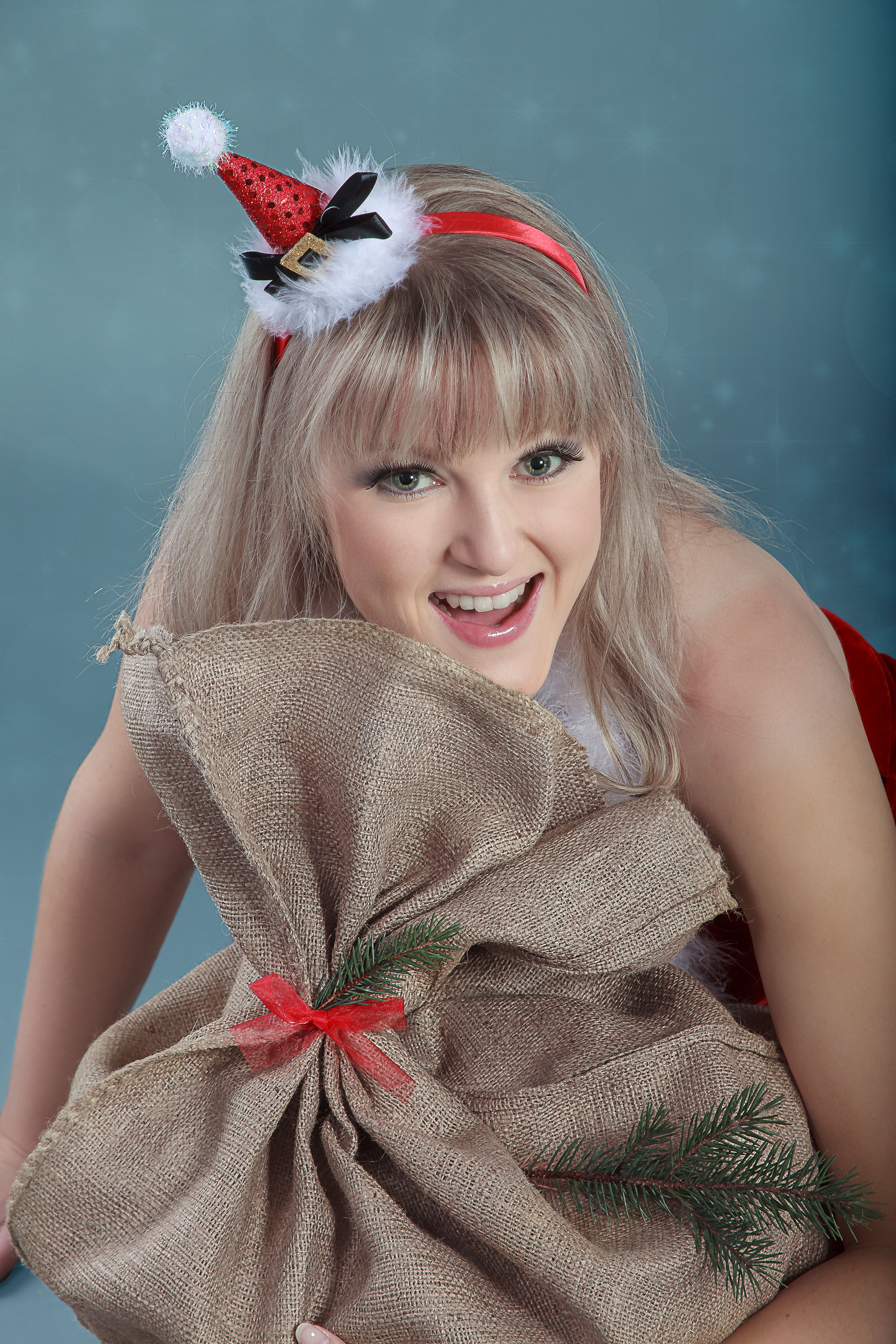 Cheerful woman in a Santa hat with a gift sack, celebrating Christmas.