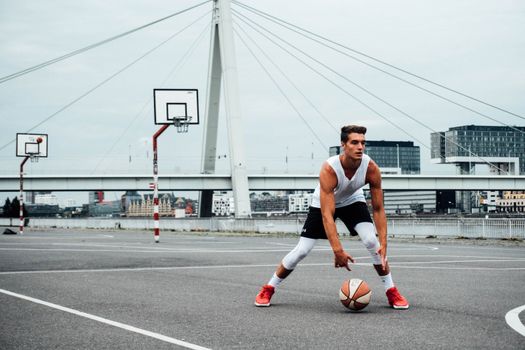 Outdoor basketball game with a young man dribbling on a city court in Cologne.