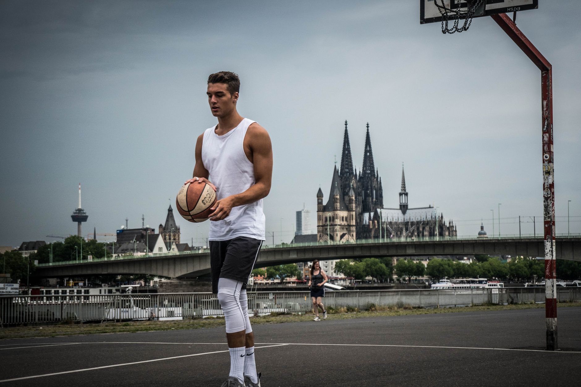 Man playing basketball outdoors near Cologne Cathedral, Germany.