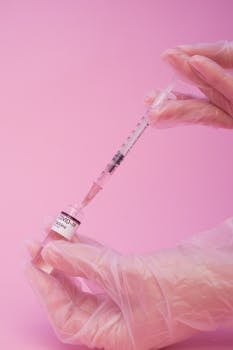 Close-up of syringe drawing COVID-19 vaccine from vial in a sterile studio environment.