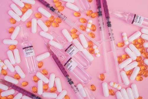Free Ampoules and syringes with coronavirus vaccine scattered on ping table with pills Stock Photo