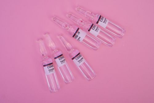 Free Top view set of sealed glass ampoules with COVID 19 vaccine arranged on pink surface Stock Photo