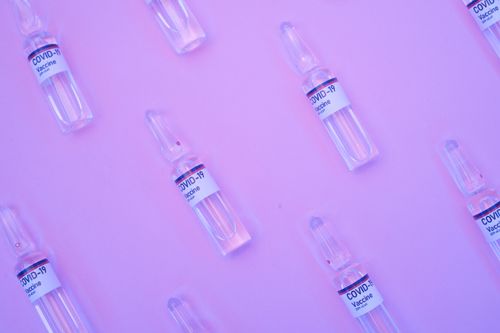 Free Background of similar ampoules with COVID 19 vaccine placed on table under neon purple light Stock Photo