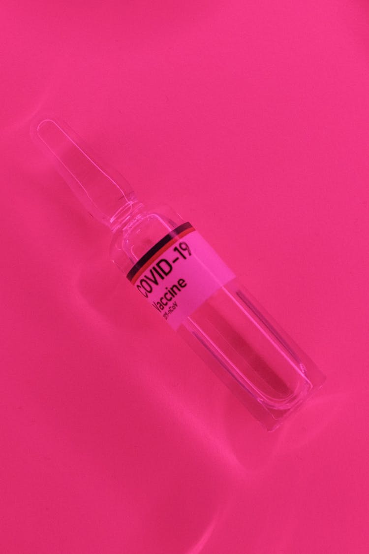 Coronavirus Vaccine In Glass Vial Laced On Vivid Pink Surface