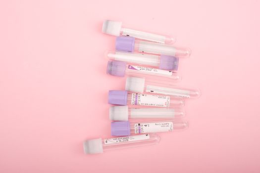 Top view of transparent glass test tubes with stickers placed on pink background
