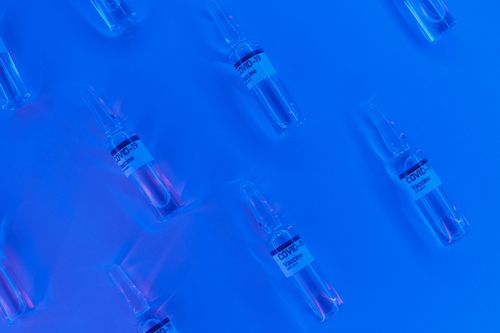 Free Top view set of COVID 19 vaccine ampoules arranged on blue background in illuminated laboratory Stock Photo