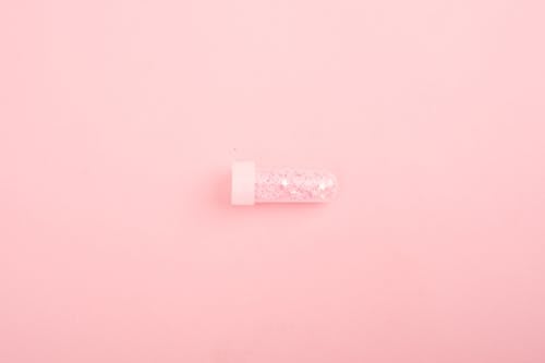 Glass tube with glitter on pink desk