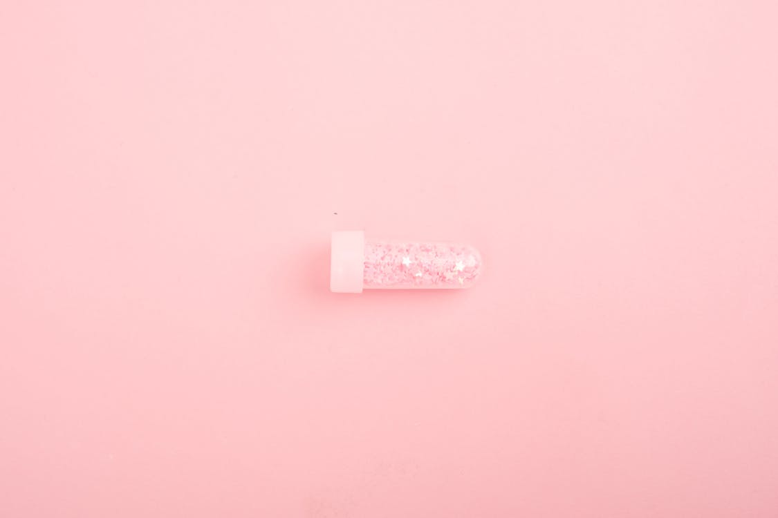 Glass tube with glitter on pink desk